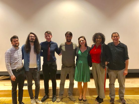 Seven people arm in arm on the stage after the screening