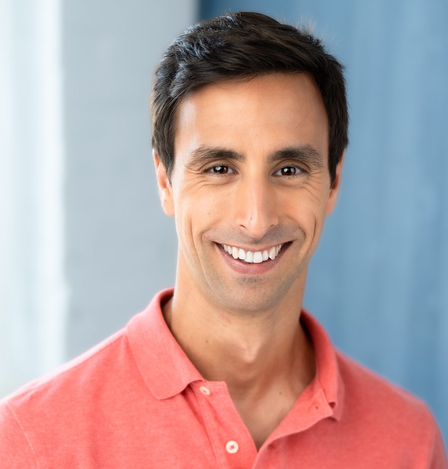 Tommy Hallal, smiling, in a coral polo shirt